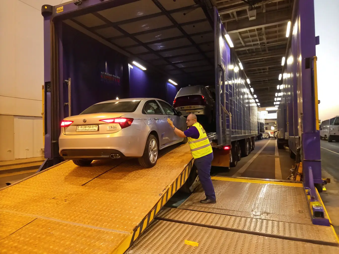 A photograph of a KoreaAuto vehicle being loaded onto a specialized transport truck, showcasing the careful handling and secure transportation methods used by the company.